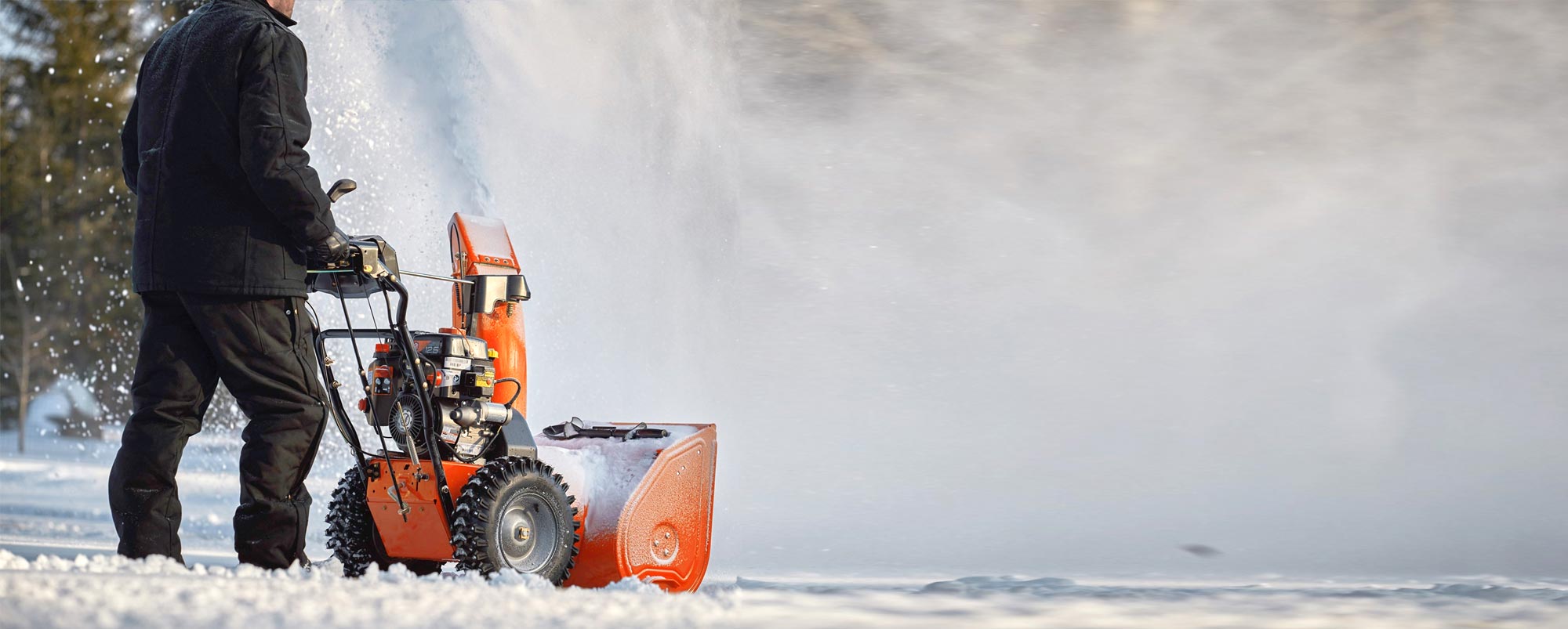 Man using an orange Ariens Snowblower to move snow in the winter